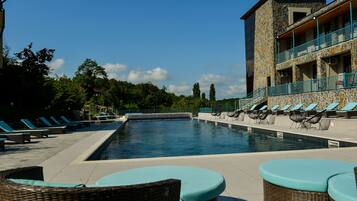 A pool area with lounge chairs and a stone building with balconies.