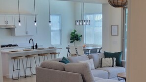 A spacious living area with a large sofa, a dining table, and a kitchen in the background.