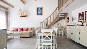 Un vaste salon comprenant un coin repas, un escalier et une vue sur l’extérieur.