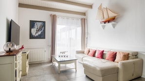 Un salon comprenant un canapé, une table basse, un téléviseur et une maquette de bateau accrochée au mur.