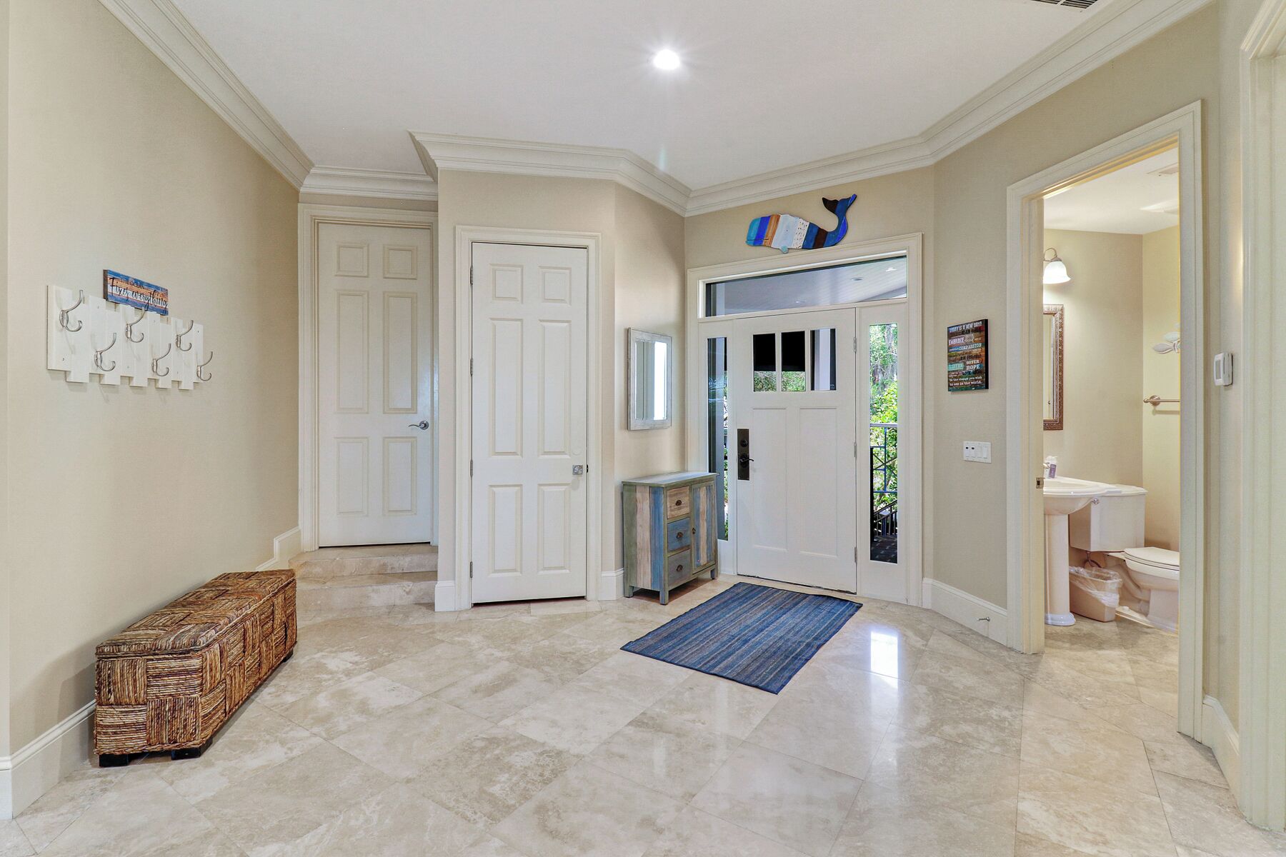 A spacious hallway with a tiled floor, a blue rug, and a rustic bench.