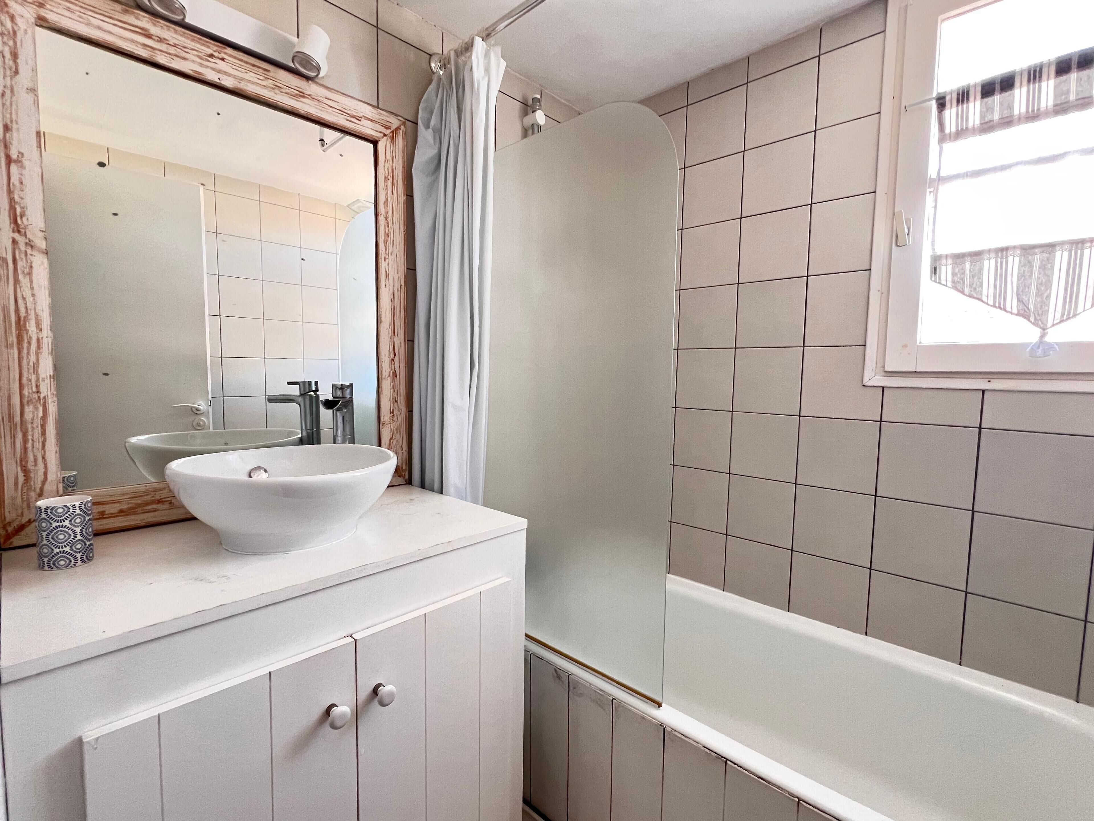 A bathroom with a white sink, mirror, and shower.