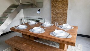 A dining table set with white plates, glasses, and cutlery, accompanied by a bench and a glass-top table. - House ANNEXE       . (Saint-Martin-de-Ré)
