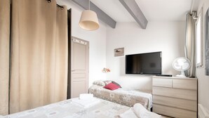 A bedroom with a bed, a TV, a dresser, and a window with curtains. - Appartment PERTUIS . (Saint-Martin-de-Ré)