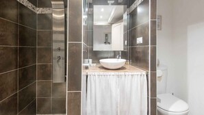 A modern bathroom with dark tiles, a white sink, and a toilet. - Appartment PERTUIS . (Saint-Martin-de-Ré)