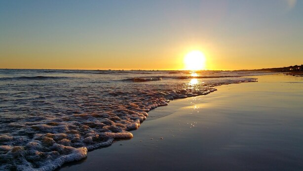 Una playa con olas al atardecer.