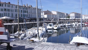 Un puerto deportivo con barcos amarrados, un paseo marítimo y edificios con señalización.