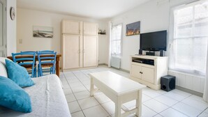 Amplia sala de estar con sofá, una mesa de centro, televisor y comedor con sillas y una mesa.