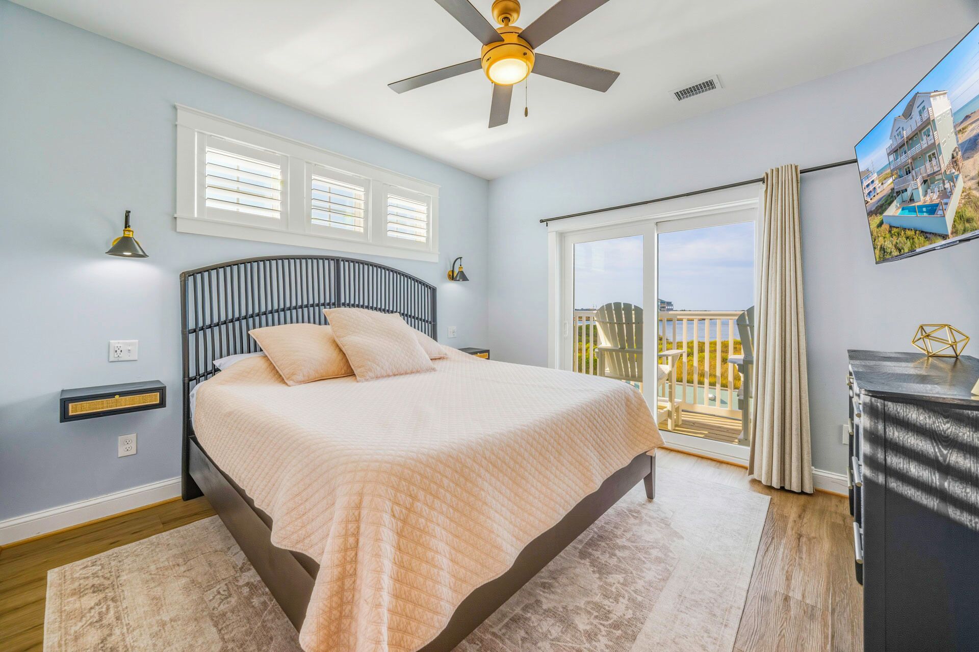 Un dormitorio con cama, ventilador de techo, calefactor, ventana y balcón con vistas.