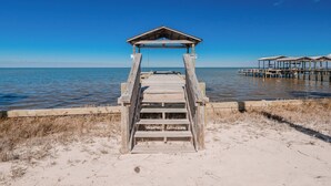 A wooden pier leading to a beach with a gazebo structure at the end. - 🌞😎Pelican Roost - 4 Bedroom Bayfront Home in Fort Morgan!😎🌞 (Gulf Shores)