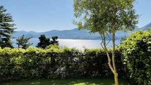 Un jardin bien entretenu, avec une pelouse, une pergola en bois et une vue sur un lac et des montagnes.