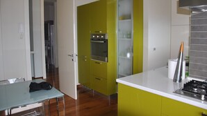 Eine moderne Küche mit grünen Schränken, einem eingebauten Backofen und einer weißen Arbeitsplatte.