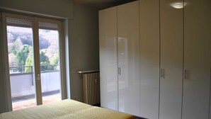 Ein Schlafzimmer mit einem Bett, einer Schiebetür zum Balkon und einem großen Kleiderschrank.