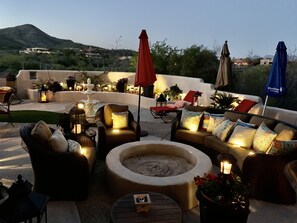 An outdoor seating area with wicker furniture, a circular fire pit, and umbrellas. - Paneramic views (Tucson)