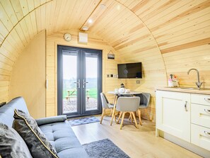 Un intérieur chaleureux, avec des éléments en bois, comprenant un canapé, une table à manger, des chaises et un coin cuisine.