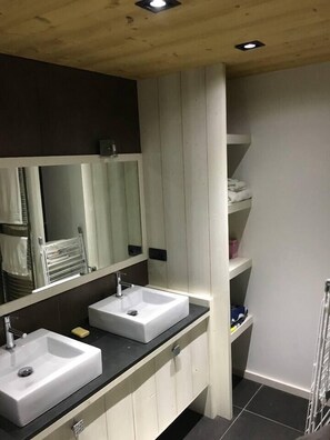Ein modernes Badezimmer mit zwei Waschbecken, einem großen Spiegel und einem Handtuchhalter.
