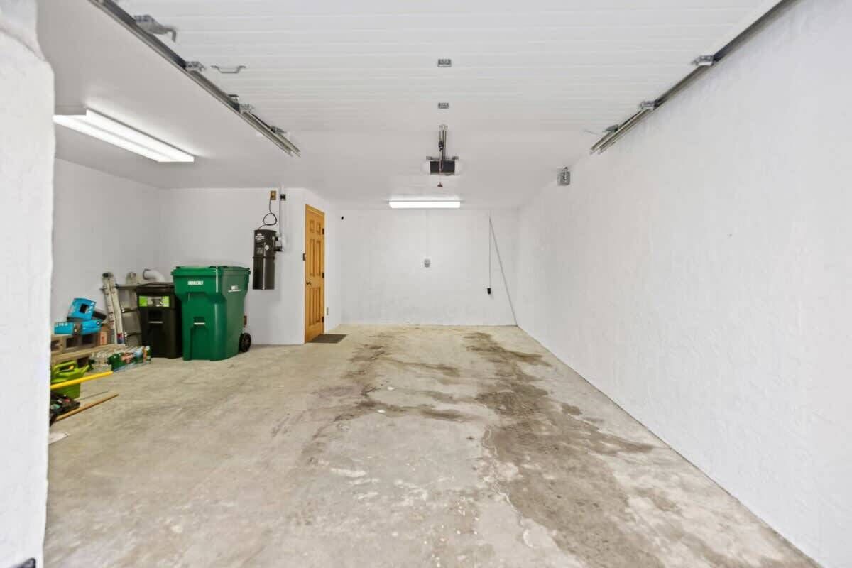 Un garage propre et vide, avec des murs blancs, un sol en béton et un éclairage fluorescent.