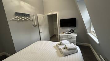 Ein Schlafzimmer mit Bett, Schminktisch, Fernseher und Fenster.