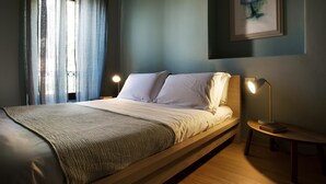 Een moderne slaapkamer met een bed, nachtkastjes en een ingelijst kunstwerk aan de muur.