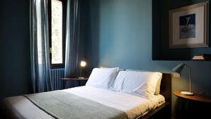A neatly made bed with white linens, a bedside lamp, and a framed picture on the wall. - Suite "Gardone" at 2 steps from the lake with panoramic view. Lounge bar and swimming pool (Faggetto Lario)