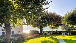A well-maintained garden with a stone pathway, lush green grass, and trees providing shade. - Suite "Anguilla" at 2 steps from the lake with panoramic view. Lounge bar and swimming pool (Faggeto Lario)