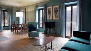A living room with a sofa, a table, a TV, and a balcony with curtains. - Suite "Luccio" at 2 steps from the lake with panoramic view. Lounge bar and swimming pool (Faggetto  Lario)