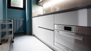 A modern kitchen with stainless steel appliances, a built-in microwave, and a window with a view of greenery.