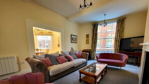 Ein Wohnzimmer mit einer Couch, Sesseln, einem Couchtisch und einem Fernseher.