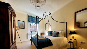 Ein Bett mit Himmelbett, eine Stehlampe und ein großer Spiegel an der Wand.