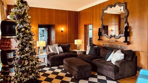 Una sala de estar acogedora con un gran árbol de Navidad, dos sofás, un tapete a cuadros y un espejo en la pared.