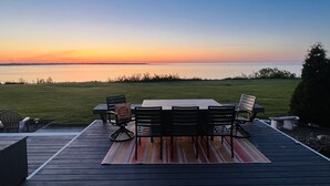 Una terraza con mesa y sillas que da a un cuerpo de agua al atardecer.