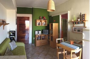 Ein kompakter Wohnraum mit grüner Wand, Holzmöbeln, einem Esstisch und einer Küchenzeile.