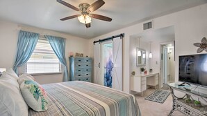 A bedroom with a bed, a ceiling fan, a dresser, a vanity, a TV, and a mirror. - Pool Access: Ranch-Style House in Sun City Center (Sun City Center)