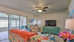 A living room with a sofa, a television, a teal cabinet, and a ceiling fan. - Pool Access: Ranch-Style House in Sun City Center (Sun City Center)