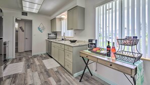 A modern kitchen with a large window, a countertop with a coffee maker, and a dining area with a table and chairs. - Pool Access: Ranch-Style House in Sun City Center (Sun City Center)