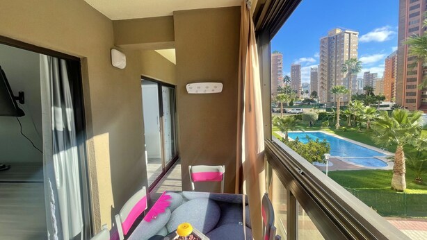 Un balcón con vista a una piscina y edificios altos.