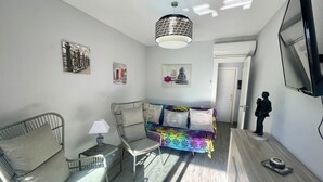 Una sala de estar moderna con un sofá, sillas, una lámpara y obras de arte en las paredes.