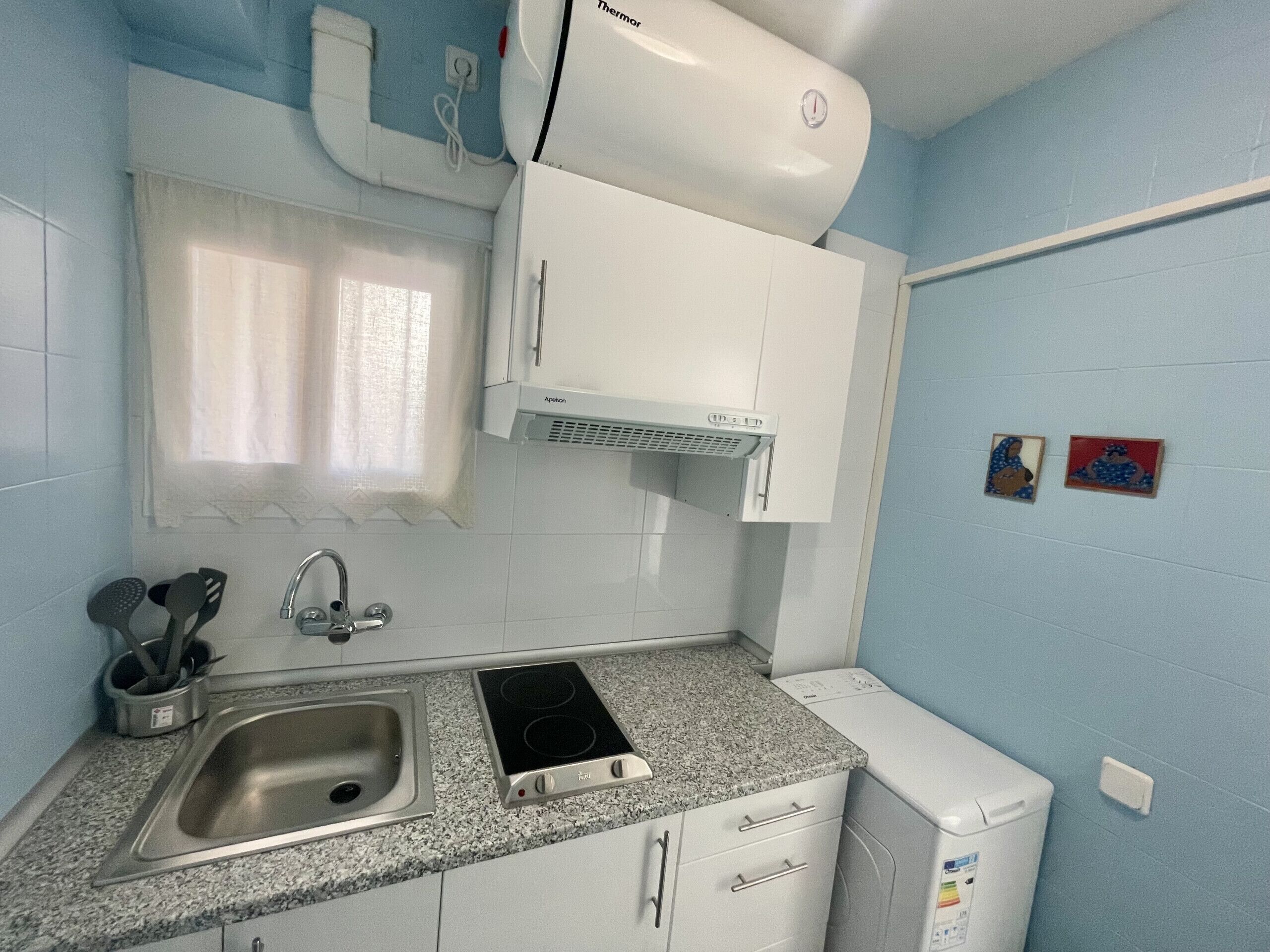 A compact kitchen with a sink, stove, and white cabinets.