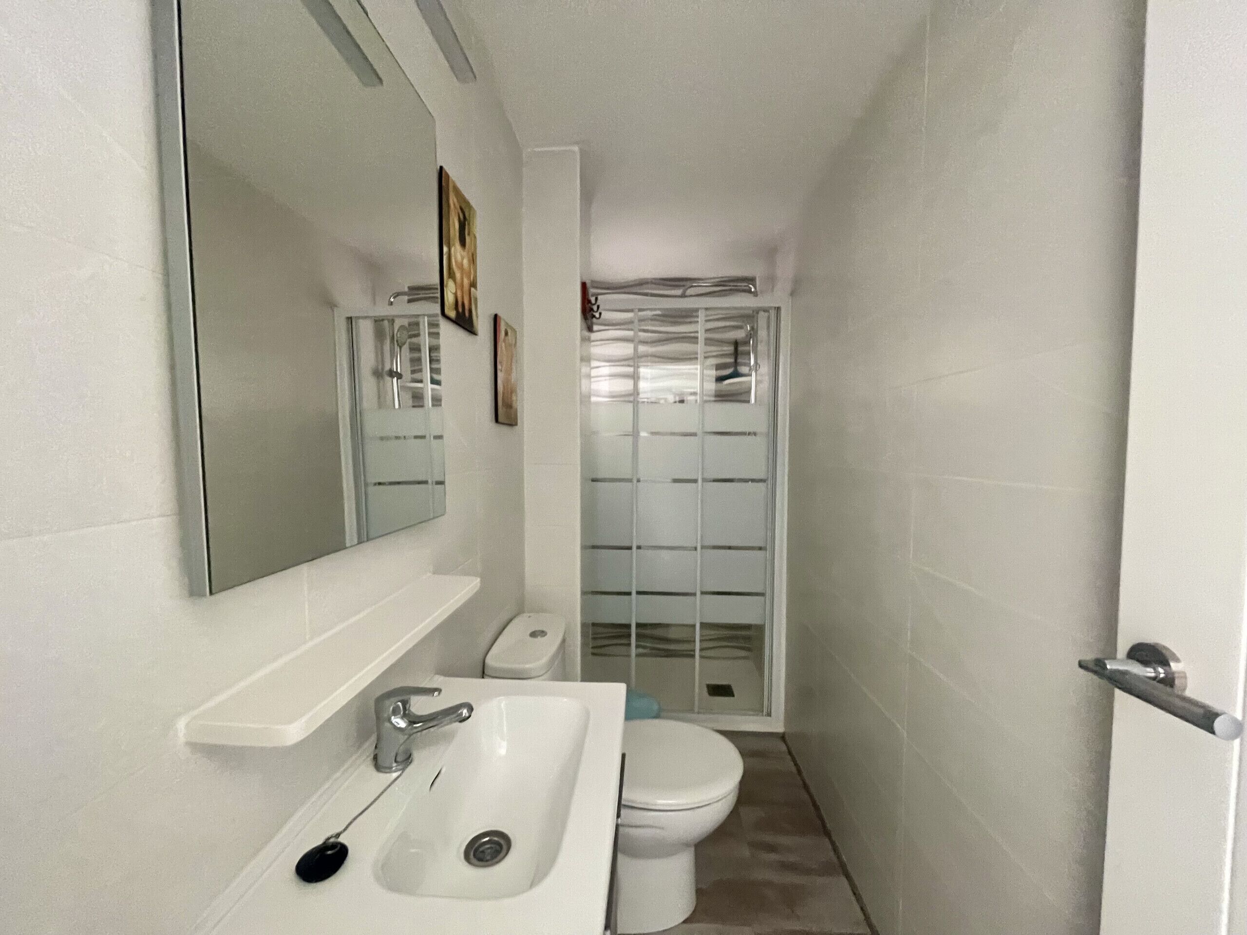 A small bathroom with a white sink, a mirror, and a toilet.
