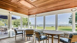 A sunroom with large windows, wicker furniture, and a view of a lake. - Minutes from Downtown Easton and St. Michaels | Pool | Private Dock | Luxury (Royal Oak)