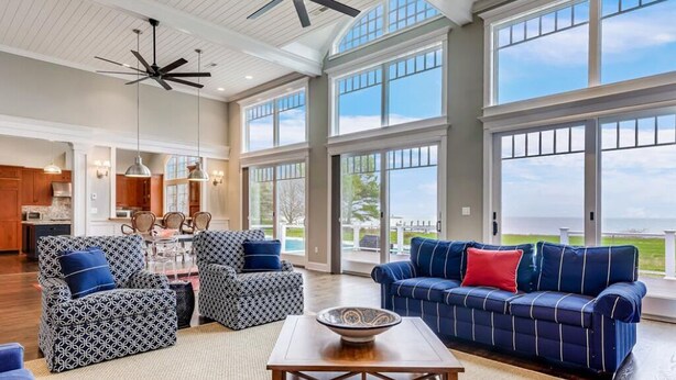 A spacious living room with a large window, a ceiling fan, and a view of the outdoors. - Minutes from Downtown Easton and St. Michaels | Pool | Private Dock | Luxury (Royal Oak)