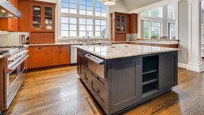 A spacious kitchen with wooden cabinets, a large island, and a view to the outside. - Minutes from Downtown Easton and St. Michaels | Pool | Private Dock | Luxury (Royal Oak)