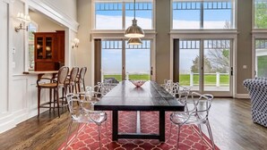 A spacious dining area with a long table, clear chairs, and a red patterned rug. - Minutes from Downtown Easton and St. Michaels | Pool | Private Dock | Luxury (Royal Oak)