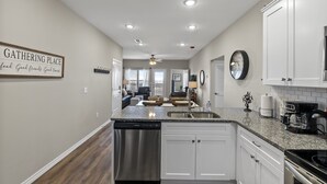 A modern kitchen with white cabinets, a stainless steel dishwasher, and a granite countertop. - Matt's Adventure Condo (Branson)