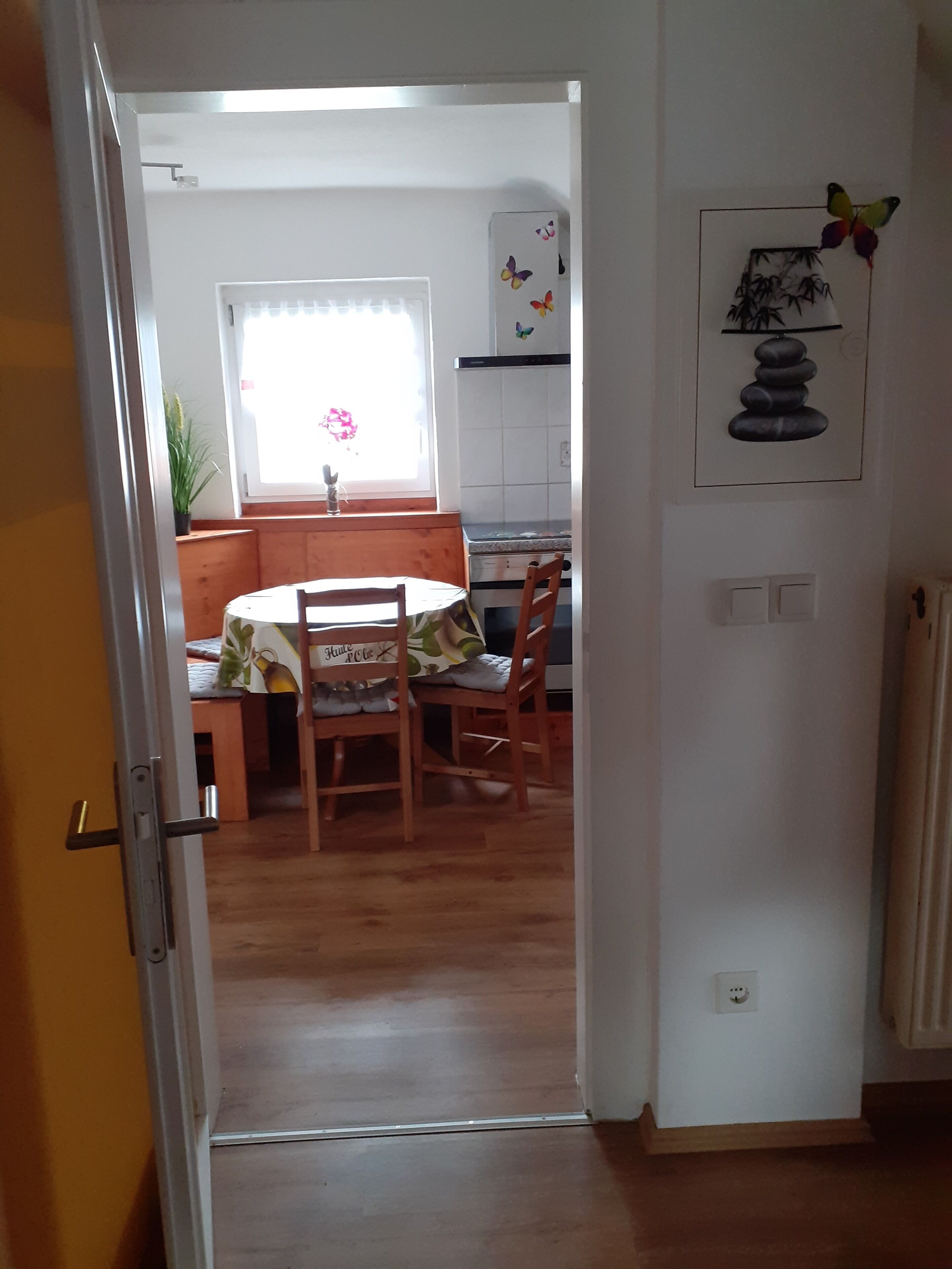 Eine Küche mit Fenster, einem Esstisch mit Stühlen und einem an der Wand hängenden Kunstwerk.