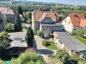 A residential area with houses featuring red-tiled roofs, a paved driveway, and surrounding greenery.