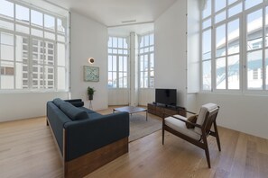 Un salon spacieux comprenant un canapé, un fauteuil, une table basse et un téléviseur.