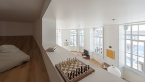 Amplia habitación con un gran tablero de ajedrez, una cama y vistas de la ciudad a través de amplios ventanales.