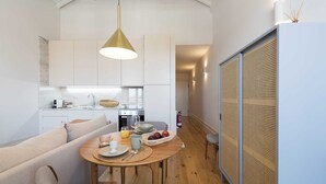 Eine moderne Küche mit weißen Schränken, einem Holztisch gedeckt mit Tellern, Tassen und einer Obstschale.