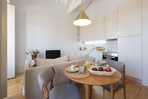A modern kitchen with white cabinets, a dining table set with plates, cups, and a fruit basket.